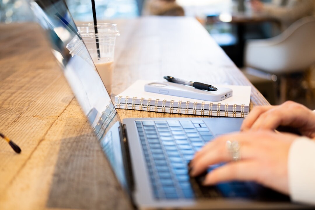 Hands typing on a laptop keyboard in a bright office